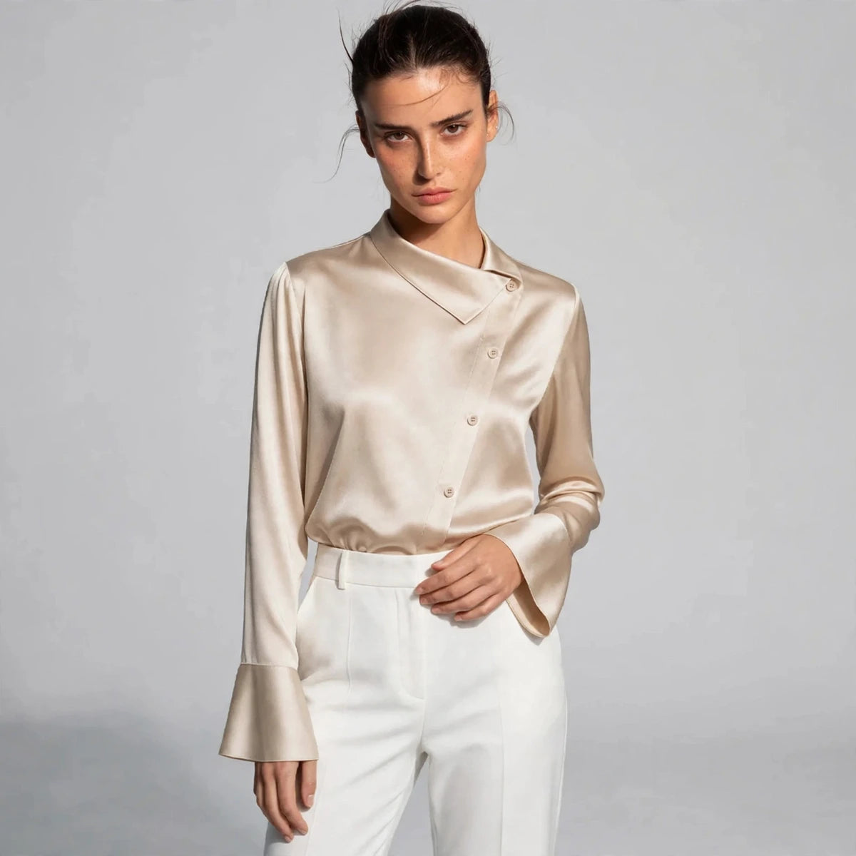 Woman wearing beige satin blouse with asymmetric collar and button front
