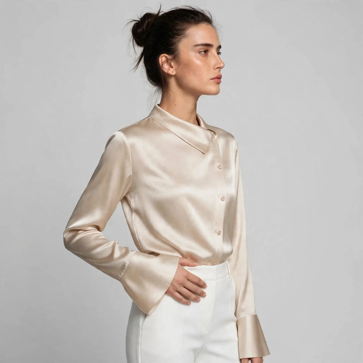 Side view of beige satin blouse showing asymmetric collar and flared cuffs