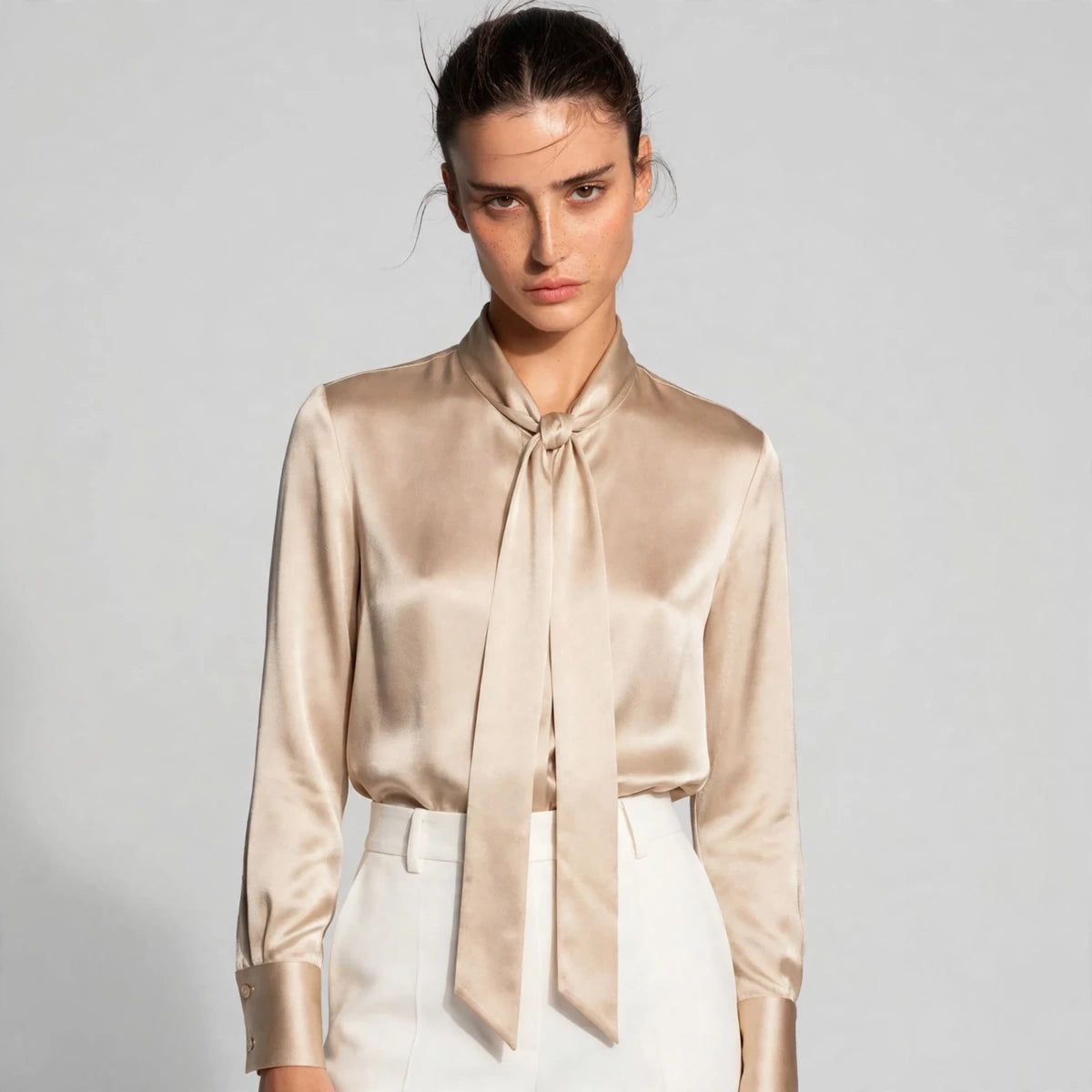 Close-up of beige satin tie-neck blouse showing knotted neck tie