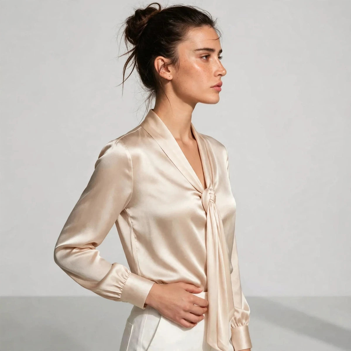 Side view of beige satin tie-neck blouse showing knotted tie and shawl collar