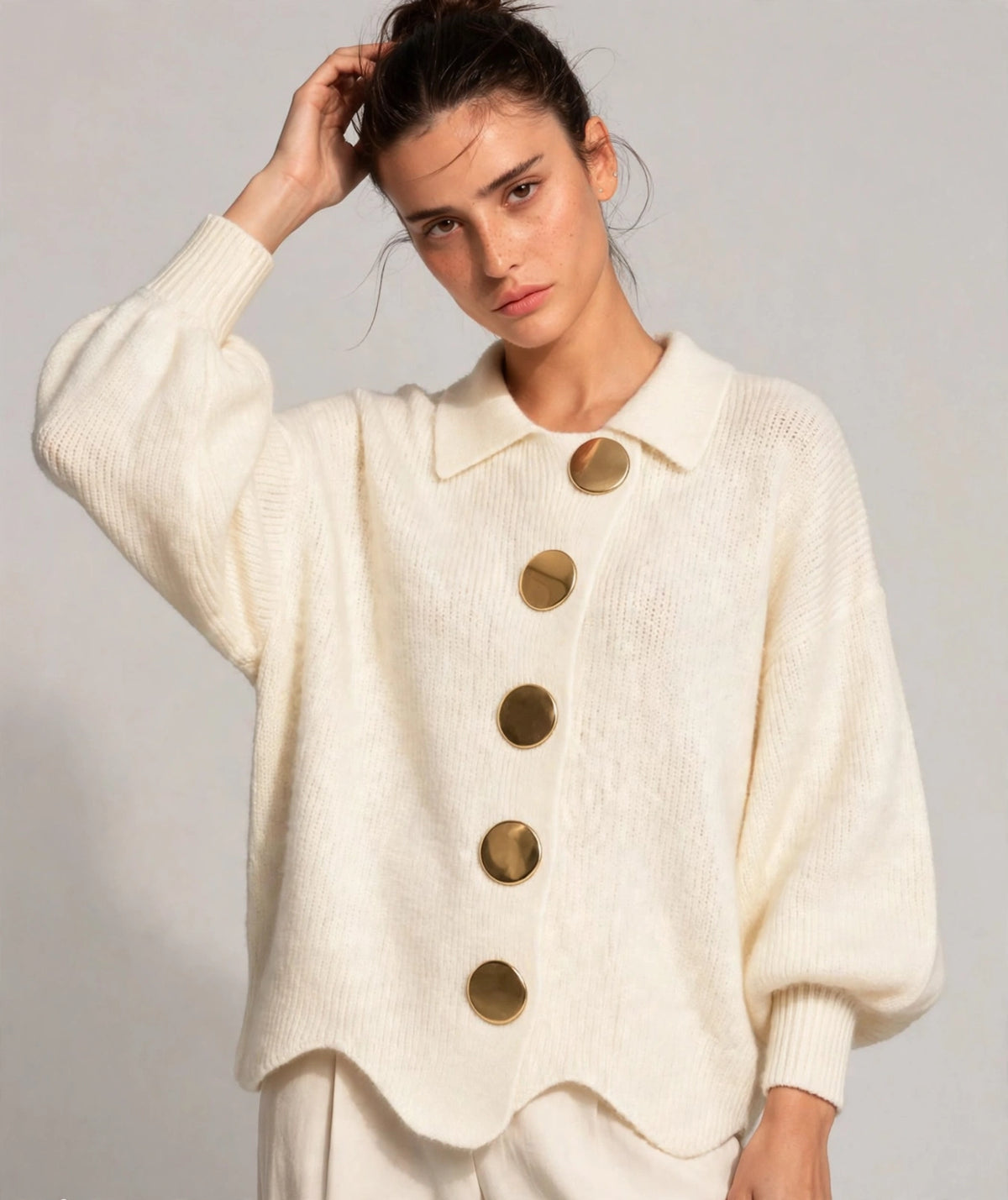Woman wearing beige gold-button knit cardigan with lantern sleeves, front view
