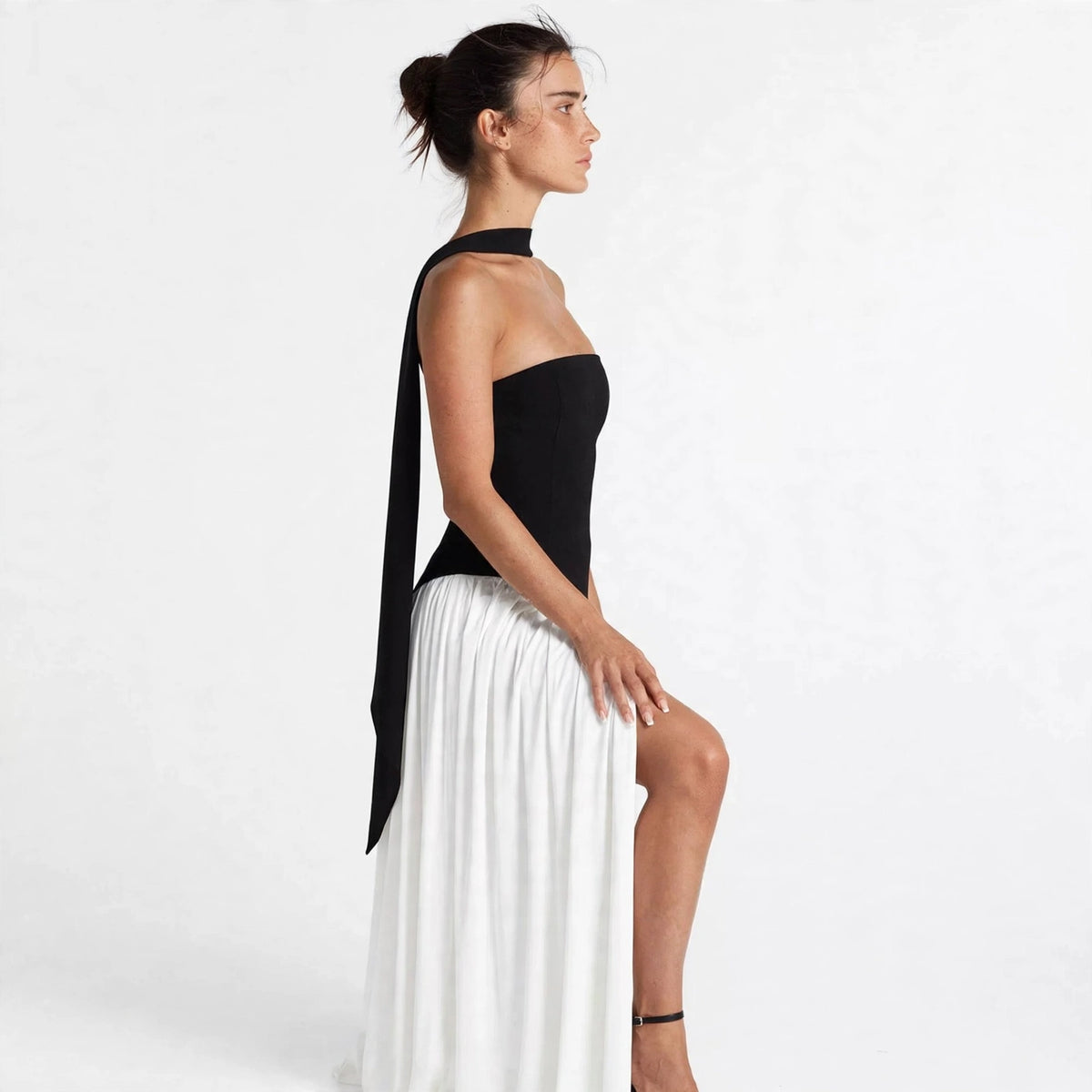 Side profile of black and white two-tone tube maxi dress with strapless bodice and white skirt