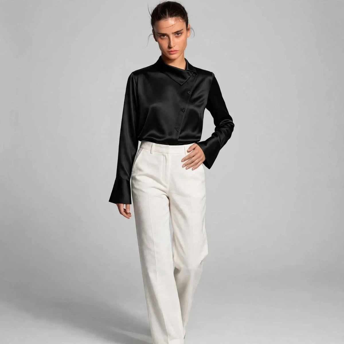Model wearing black satin collar blouse with white trousers in a fashion editorial