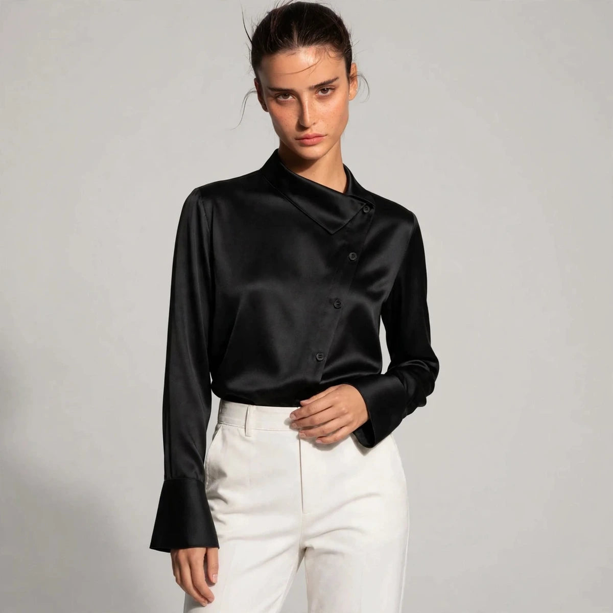Woman wearing black satin blouse with asymmetric collar and flared cuffs