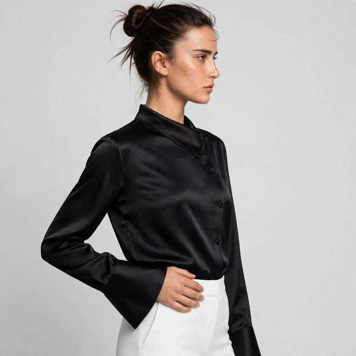 Side view of black satin blouse showing asymmetric collar and flared cuffs