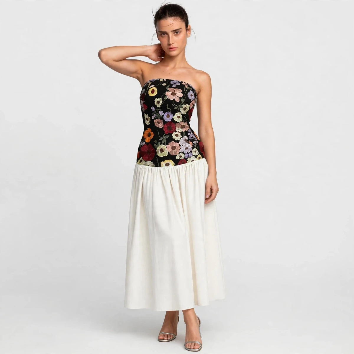Woman wearing black floral embroidered tube maxi dress with white skirt, front view