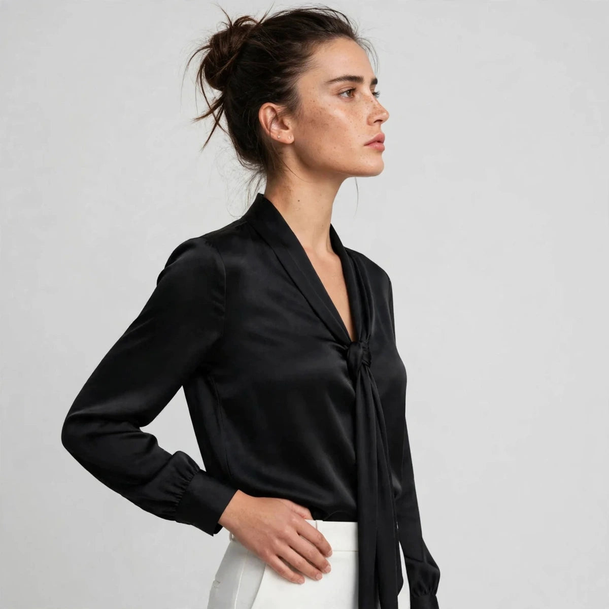 Side view of black satin tie-neck blouse showing knotted tie detail