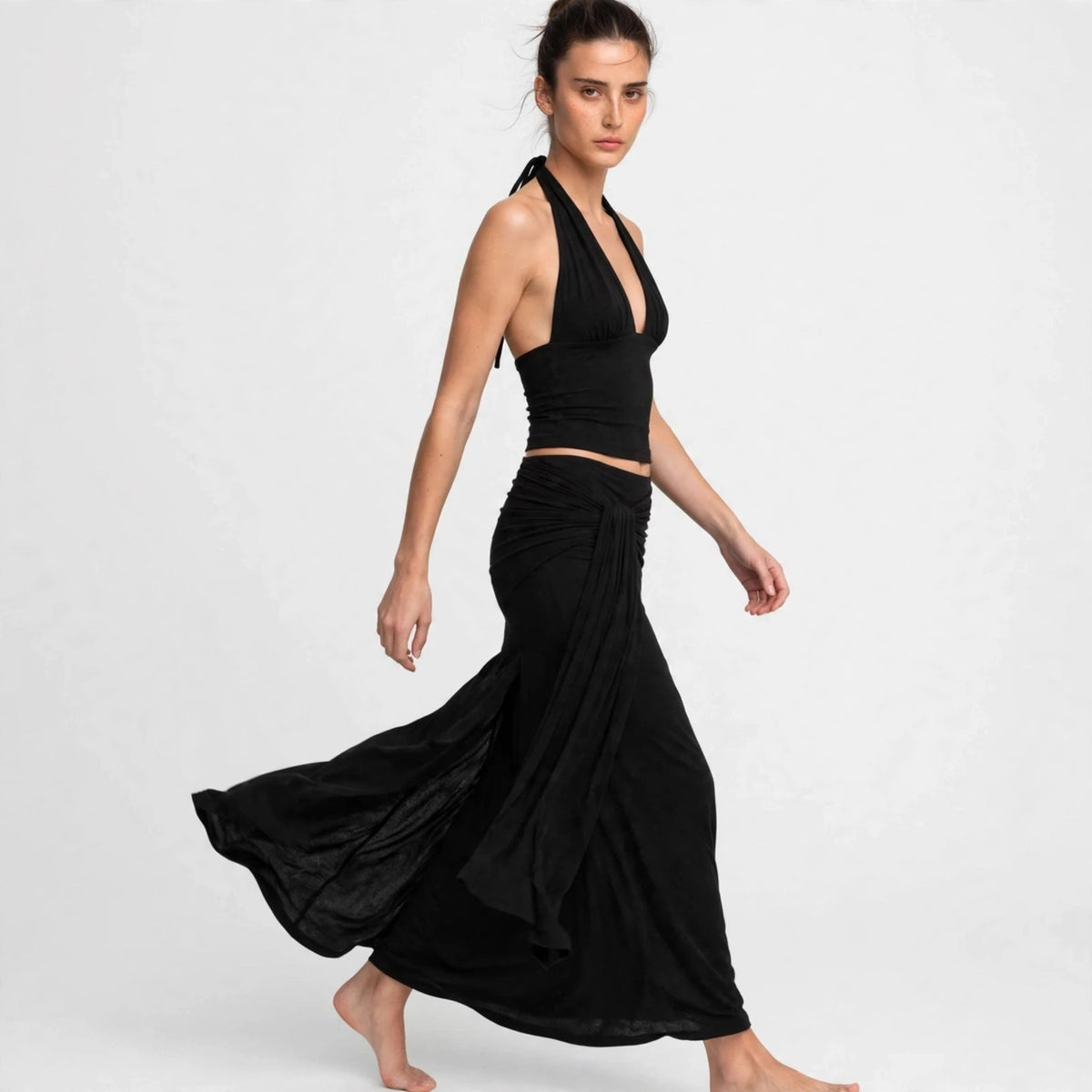 Woman wearing black halter crop top and draped maxi skirt set