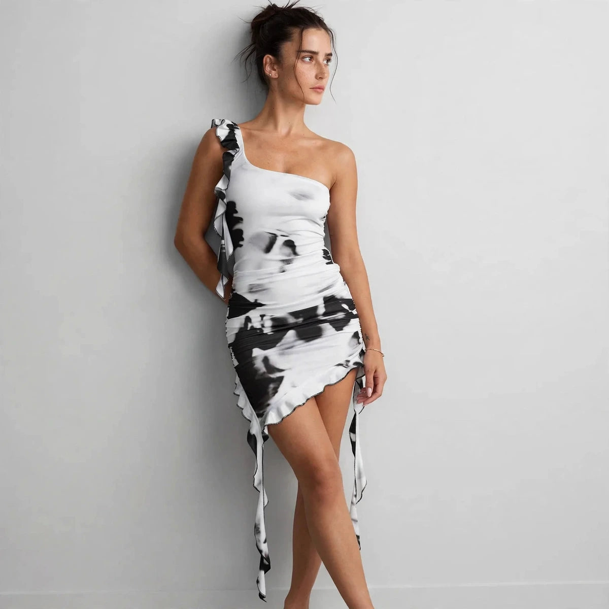 Front view of black tie-dye ruffled one-shoulder mini dress with asymmetric hem