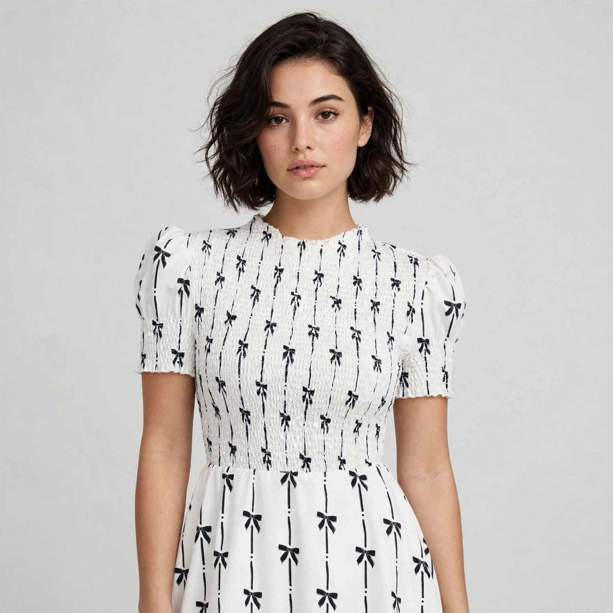 Close-up of white bow print dress showing smocked bodice and puff sleeves