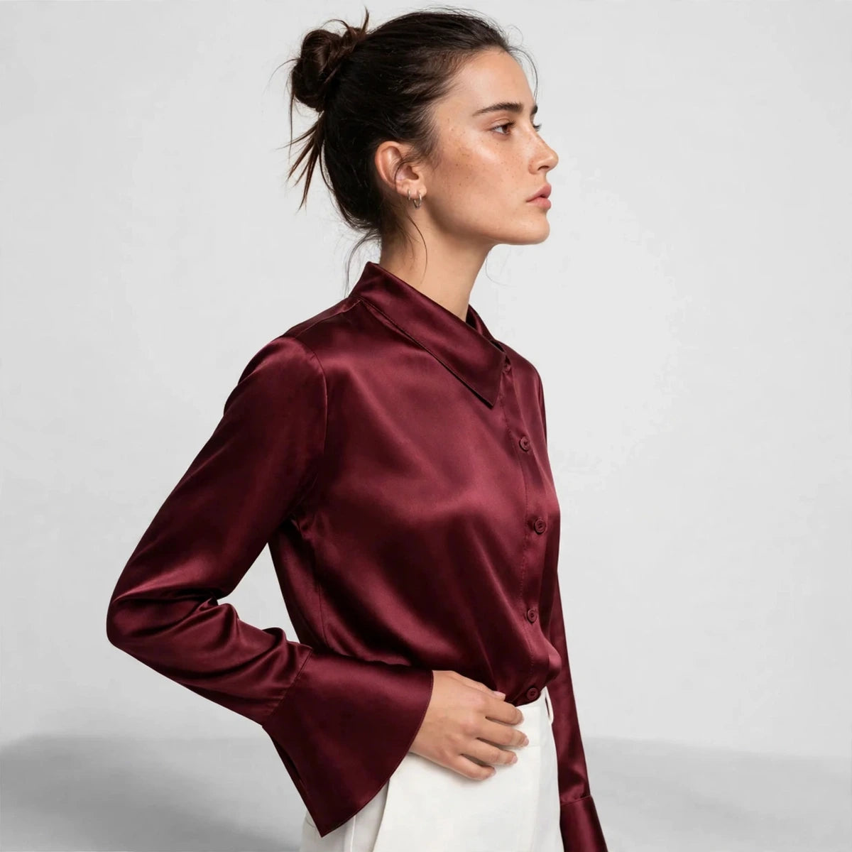 Side view of burgundy satin blouse showing asymmetric collar and flared cuffs