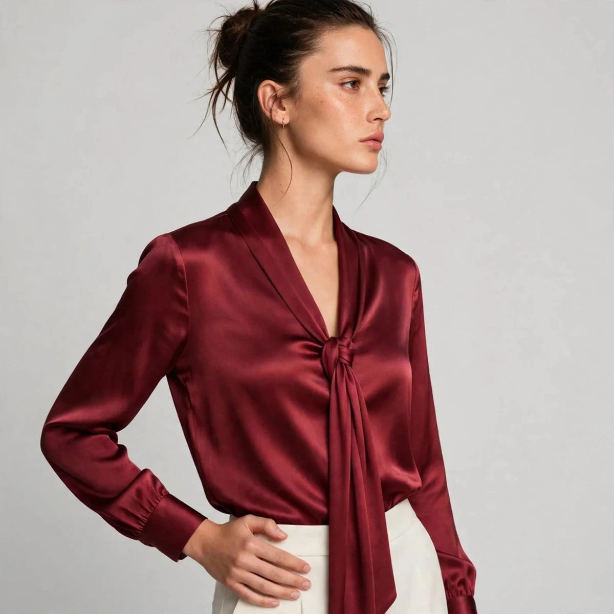 Side view of burgundy satin tie-neck blouse showing knotted tie detail