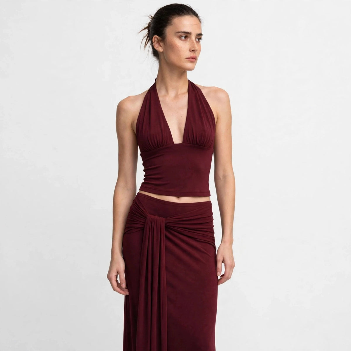 Woman wearing burgundy halter top and draped maxi skirt set