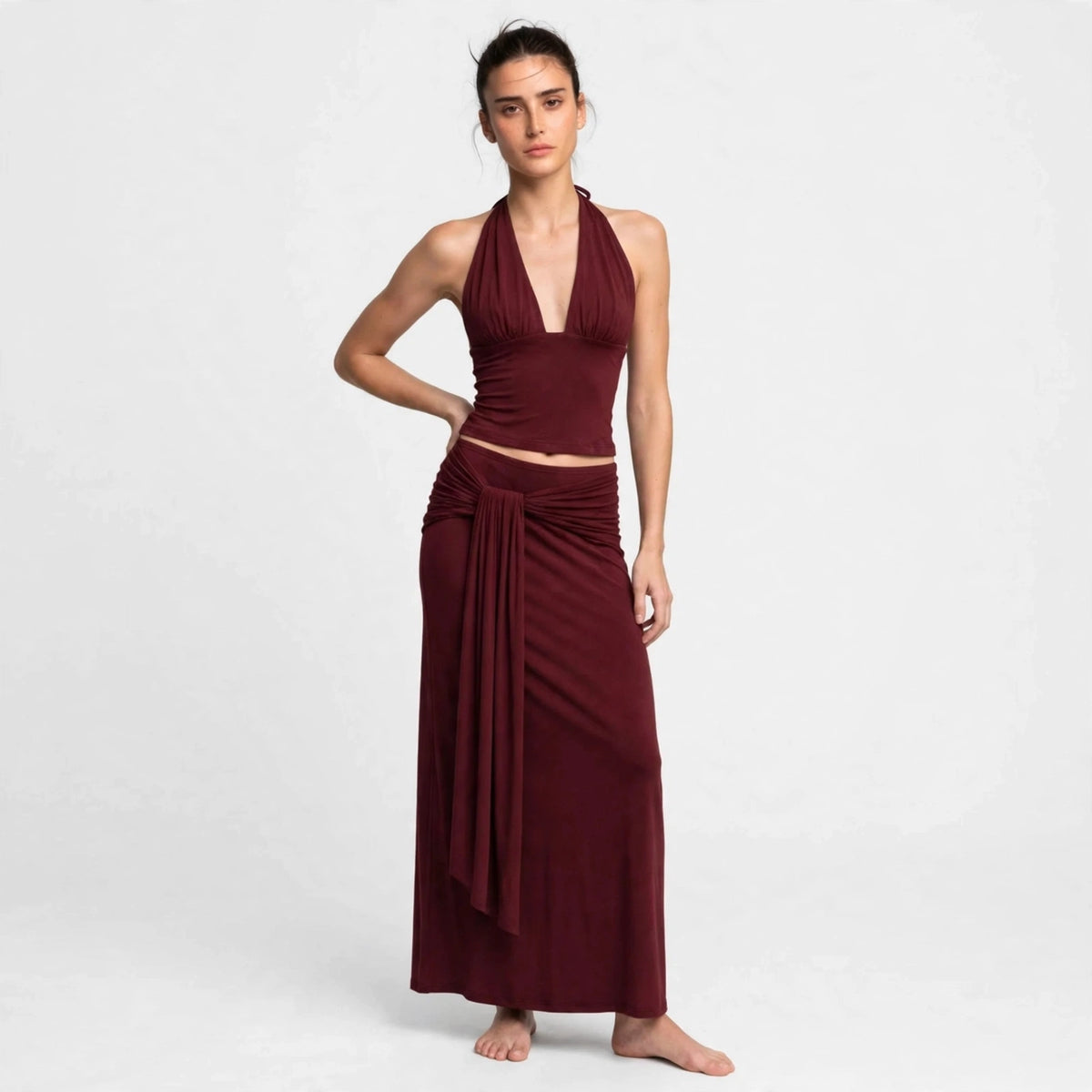 Side view of burgundy halter skirt set with twisted waist drape
