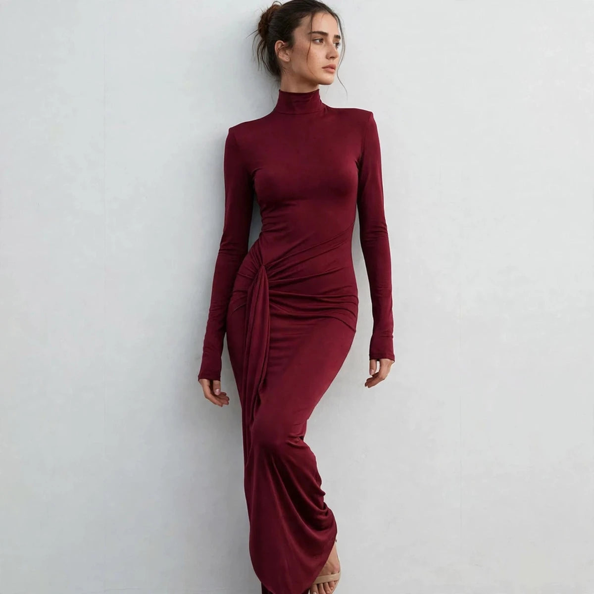 Model leaning in burgundy turtleneck maxi dress with tie waist, side view
