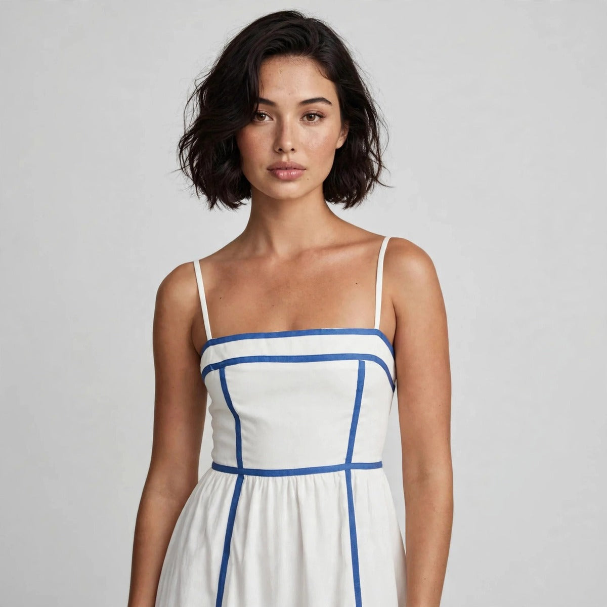 Close-up of white cami midi dress bodice with blue piping trim