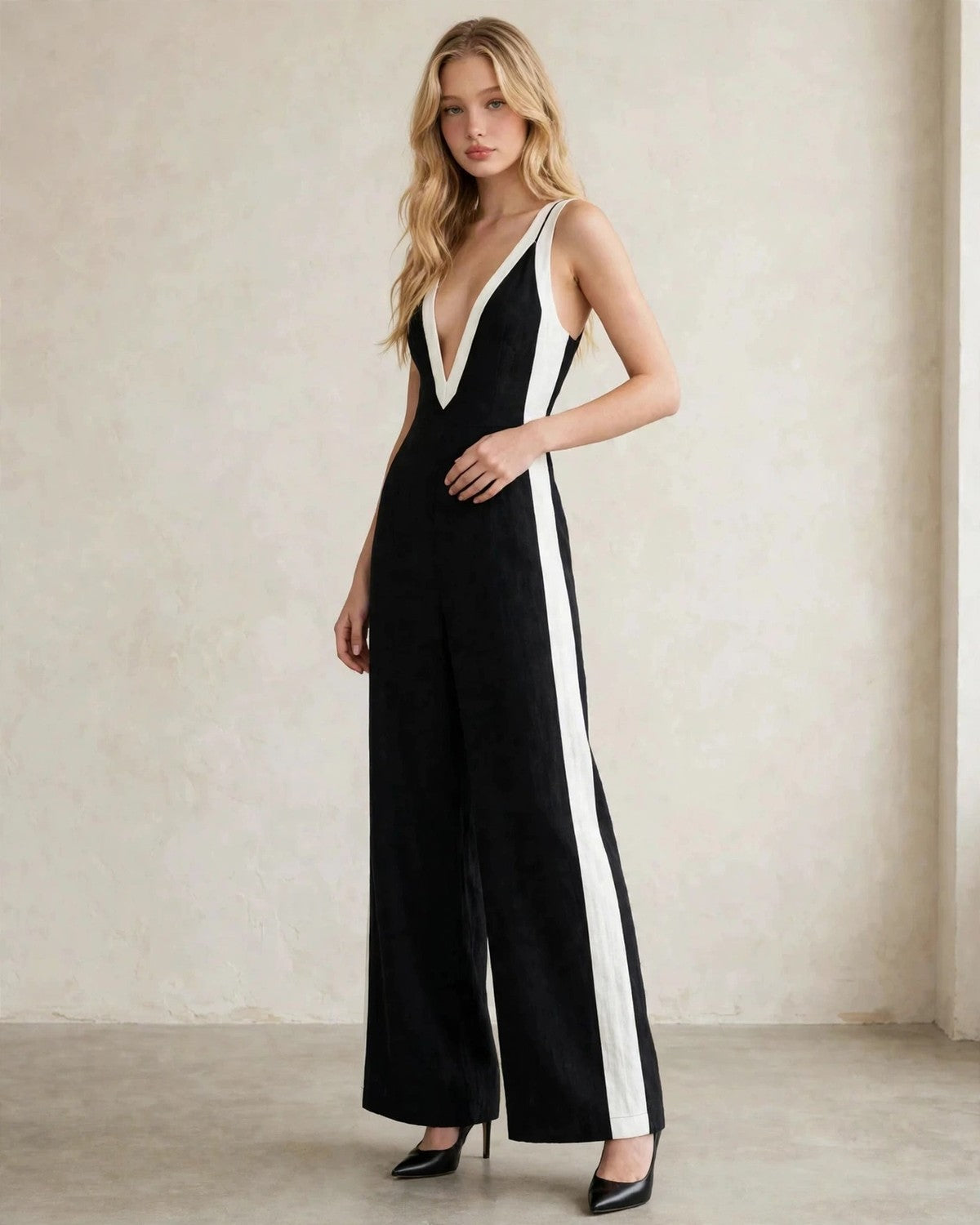 Women's contrast trim sleeveless jumpsuit in black with white trim, hand at waist pose
