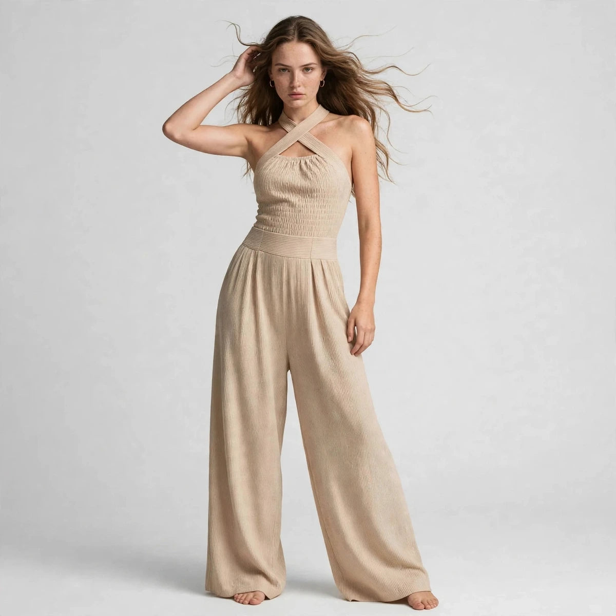 Model wearing a beige crisscross halter jumpsuit in a fashion editorial