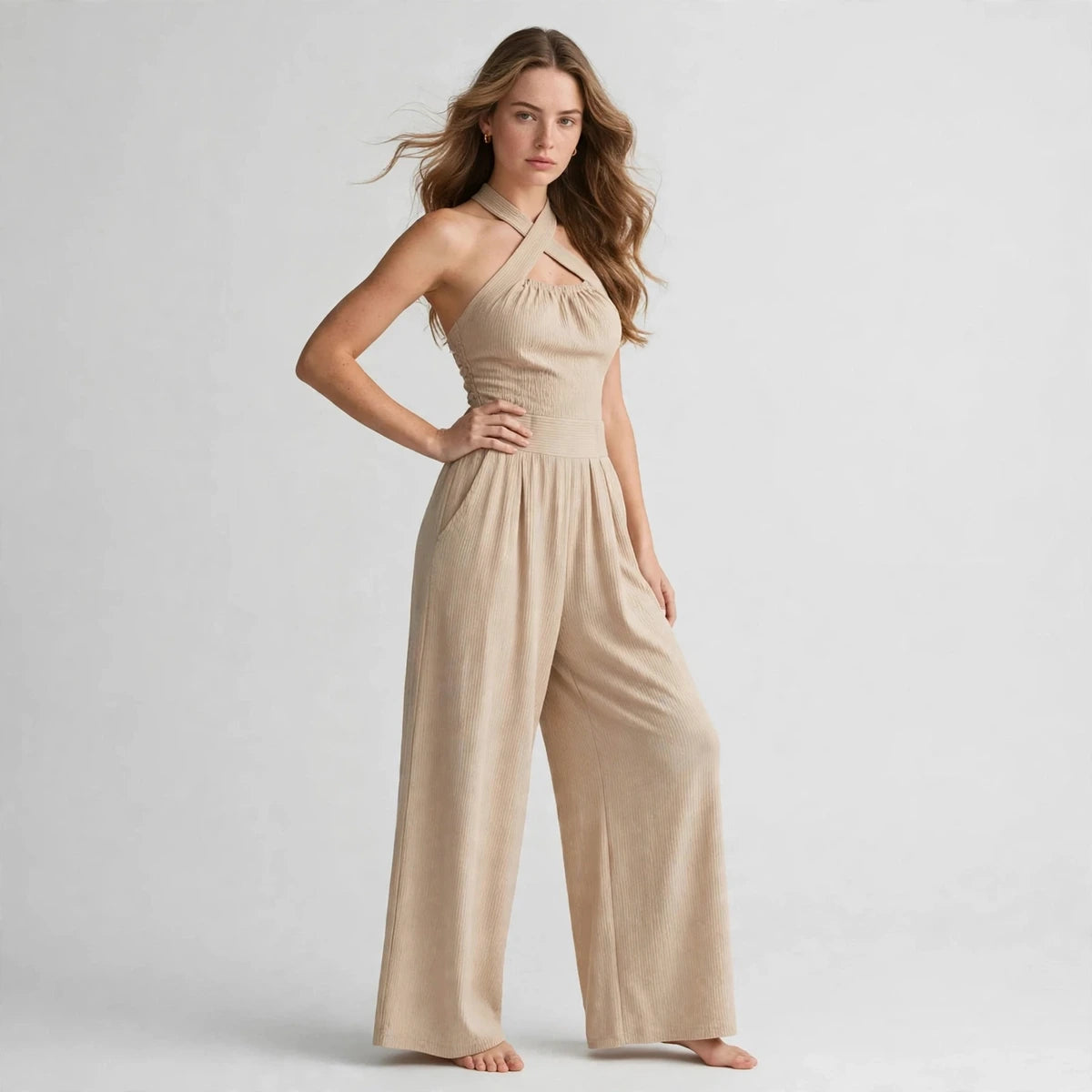 Woman wearing a beige crisscross halter jumpsuit with pleated wide-leg pants, front view