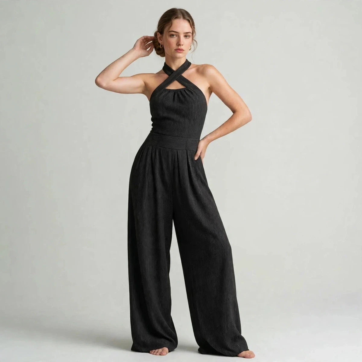 Model wearing a black crisscross halter jumpsuit with a wide-leg fit in a fashion editorial