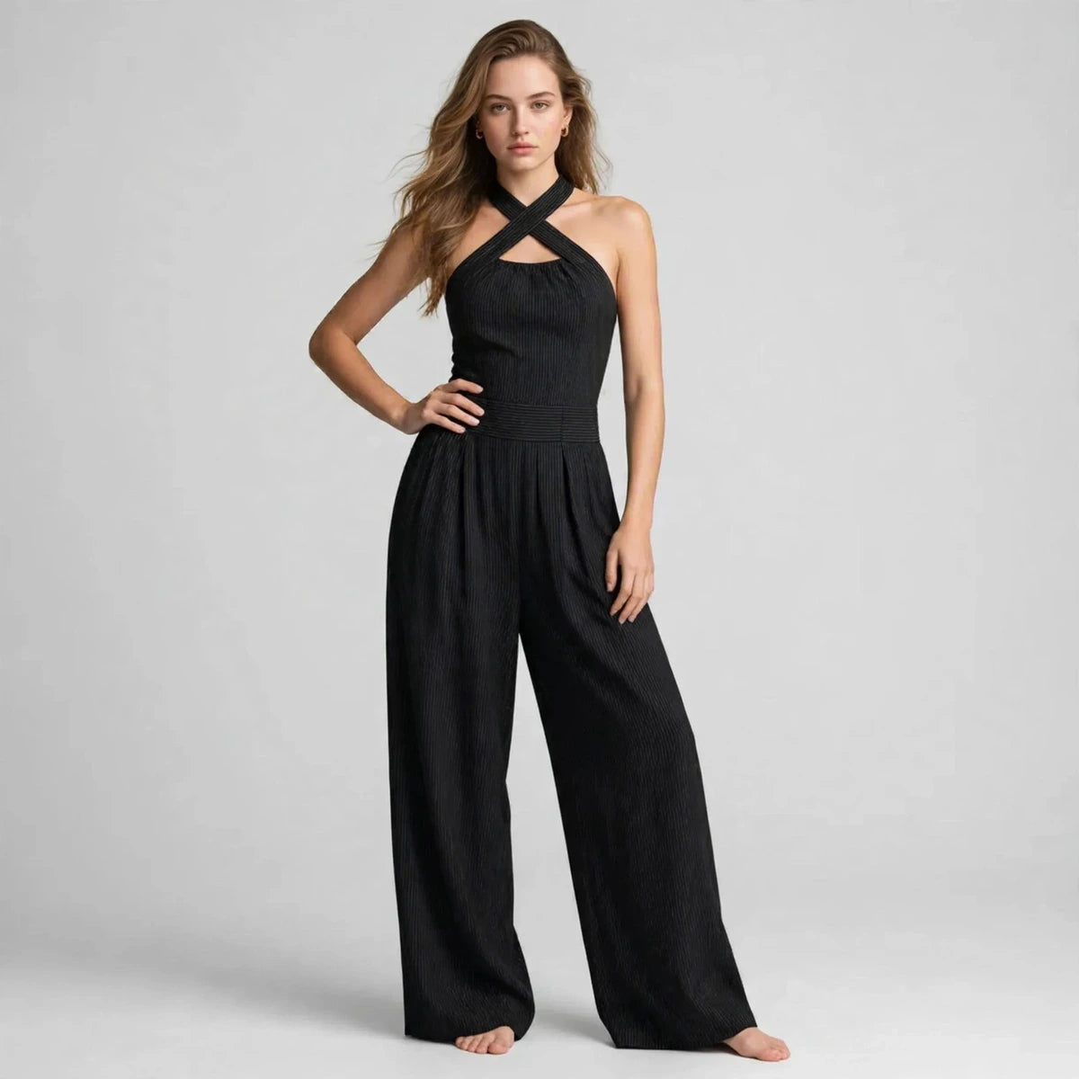 Woman wearing a black crisscross halter jumpsuit with a ribbed waistband, front view
