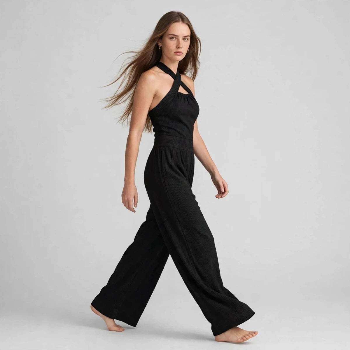 Side view of a black crisscross halter jumpsuit showing the wide-leg silhouette