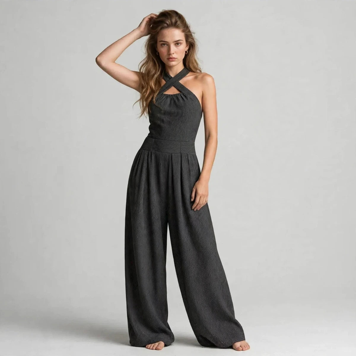 Model wearing a dark gray crisscross halter jumpsuit in a fashion editorial