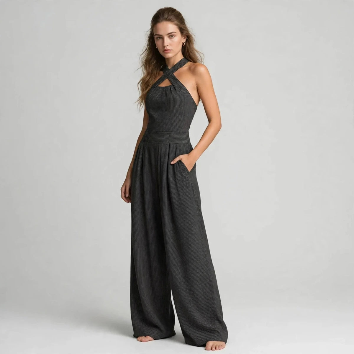 Woman in a dark gray crisscross halter jumpsuit with her hand in the pocket