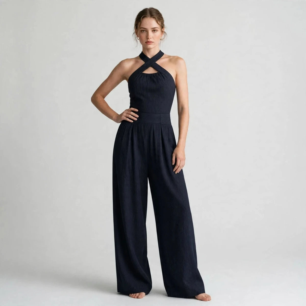 Model wearing a dark navy crisscross halter jumpsuit in a fashion editorial