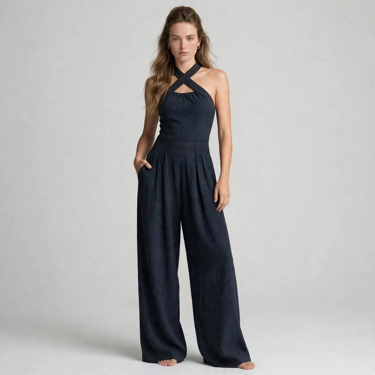 Woman wearing a dark navy crisscross halter jumpsuit with a ribbed waistband, front view