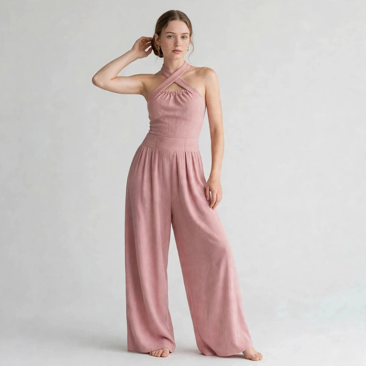 Model wearing a dusty pink crisscross halter jumpsuit in a fashion editorial