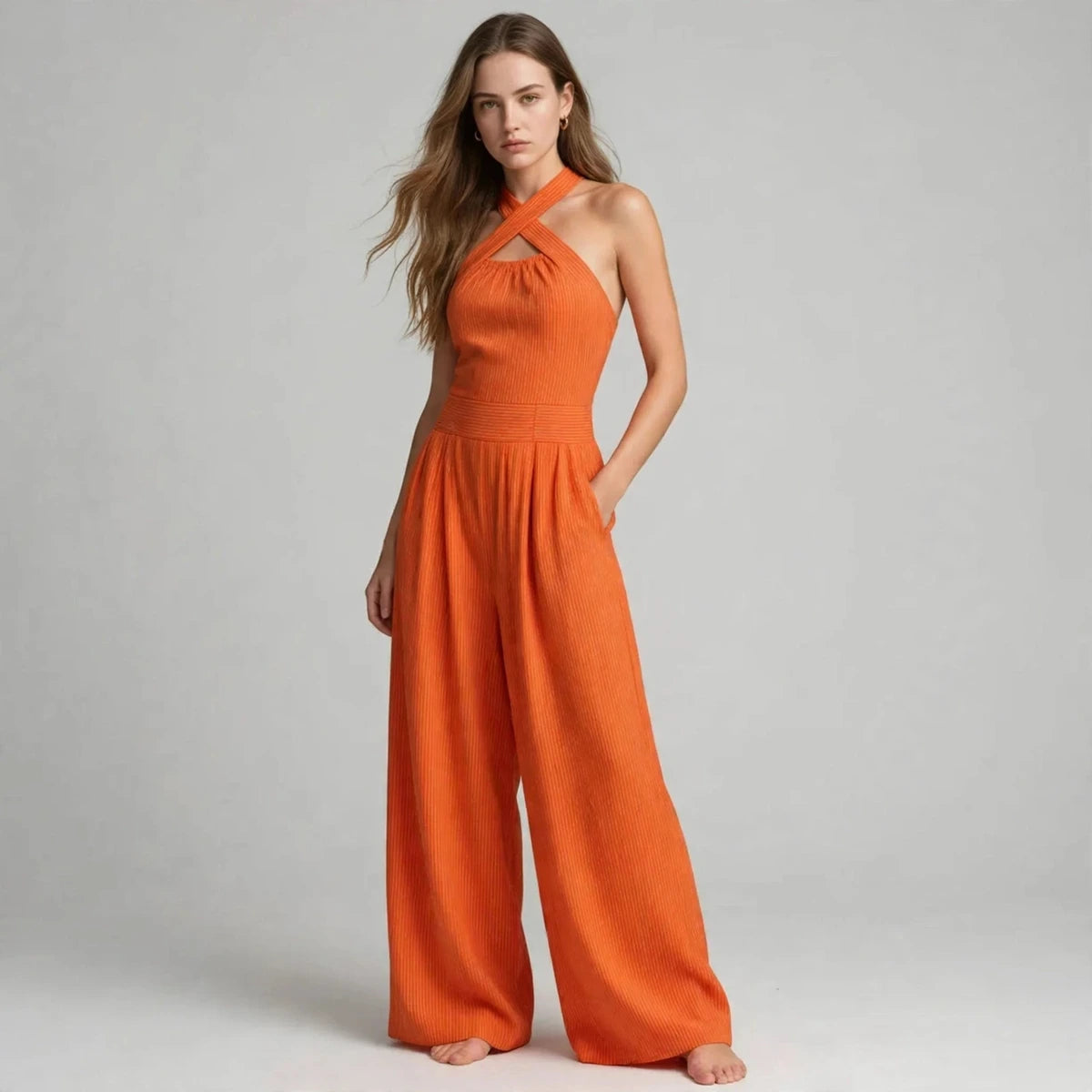 Woman in an orange crisscross halter jumpsuit with her hand in the pocket