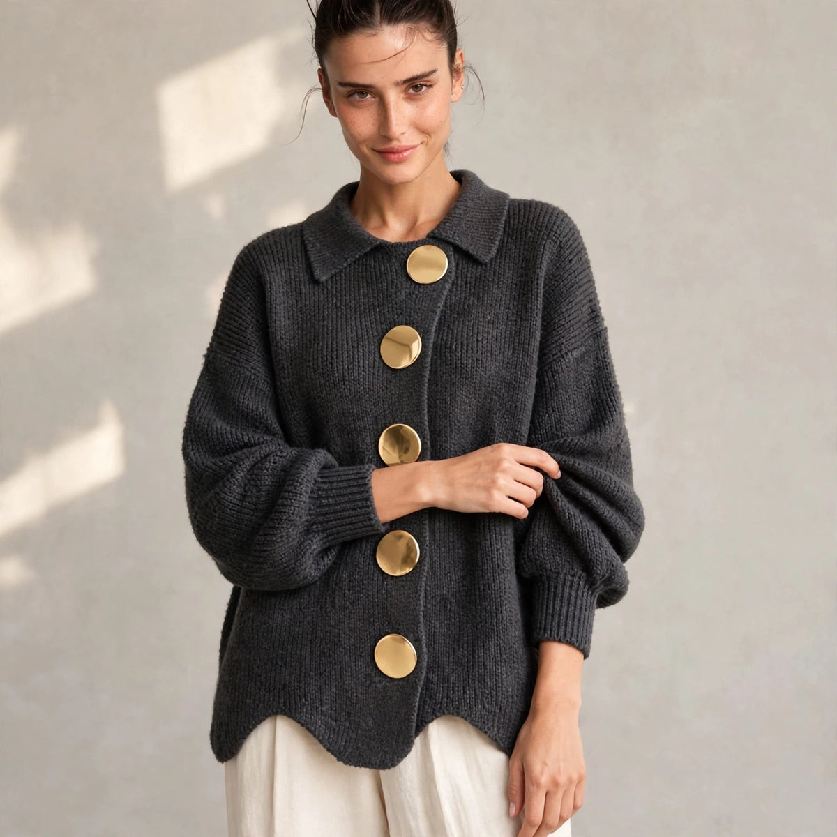 Woman wearing dark gray gold-button knit cardigan with lantern sleeves, front view