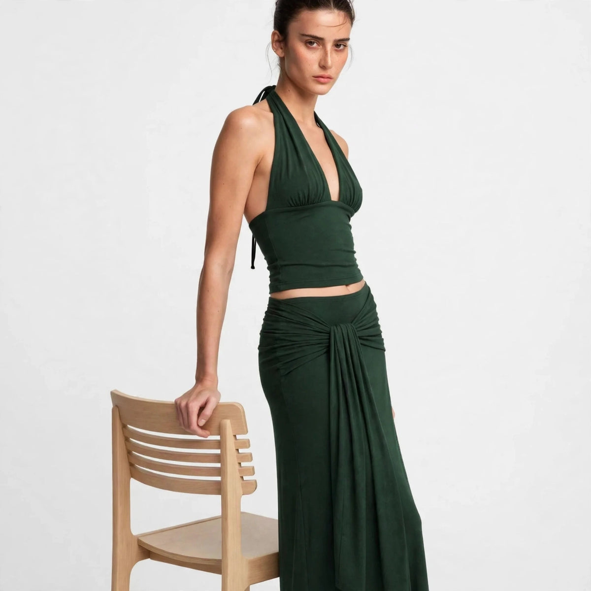 dark green halter crop top maxi skirt set – front view, leaning on chair