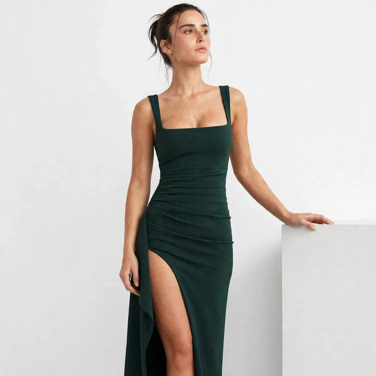 dark green ruched high slit maxi dress – three-quarter view, leaning on block
