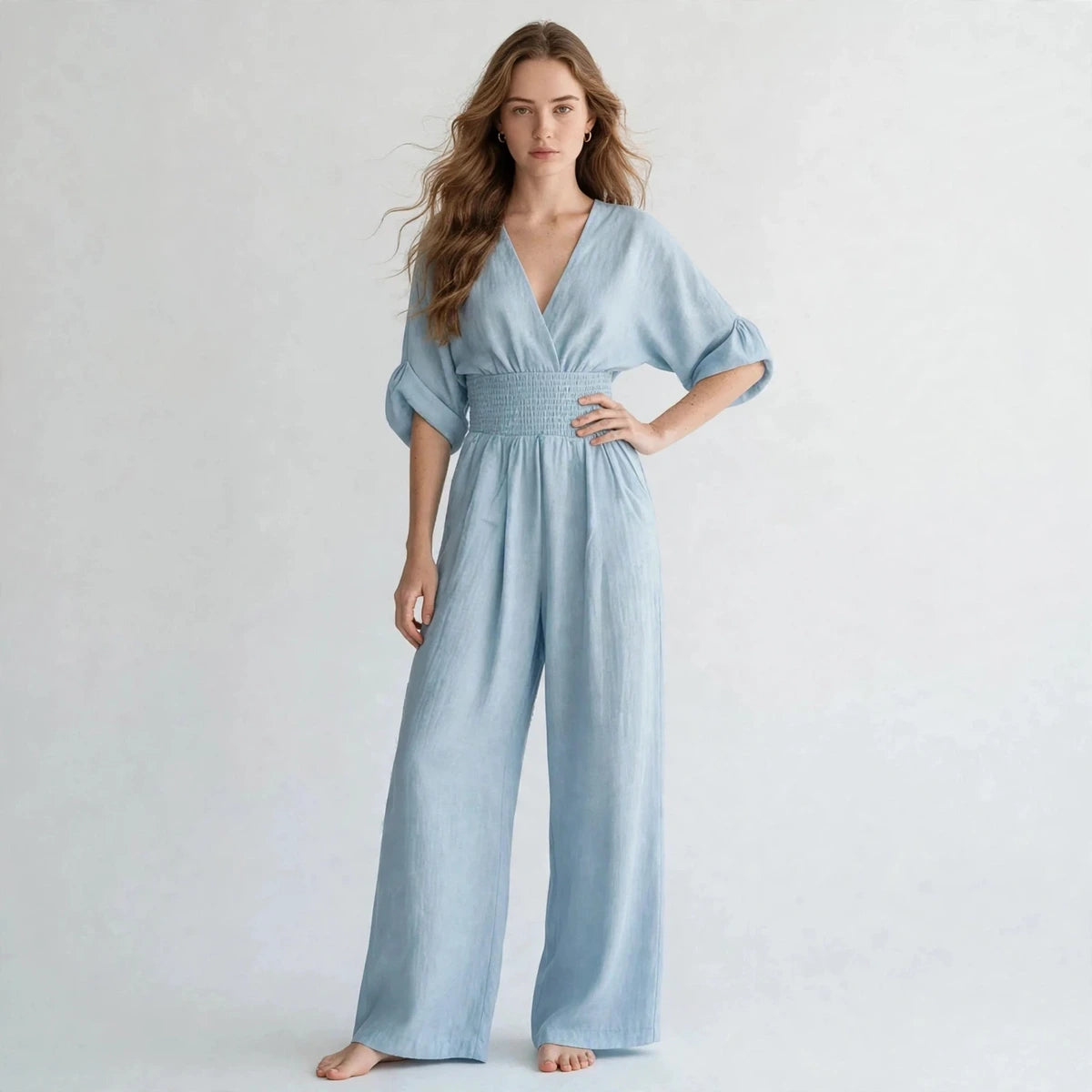 Woman wearing light blue half sleeve jumpsuit with smocked waist