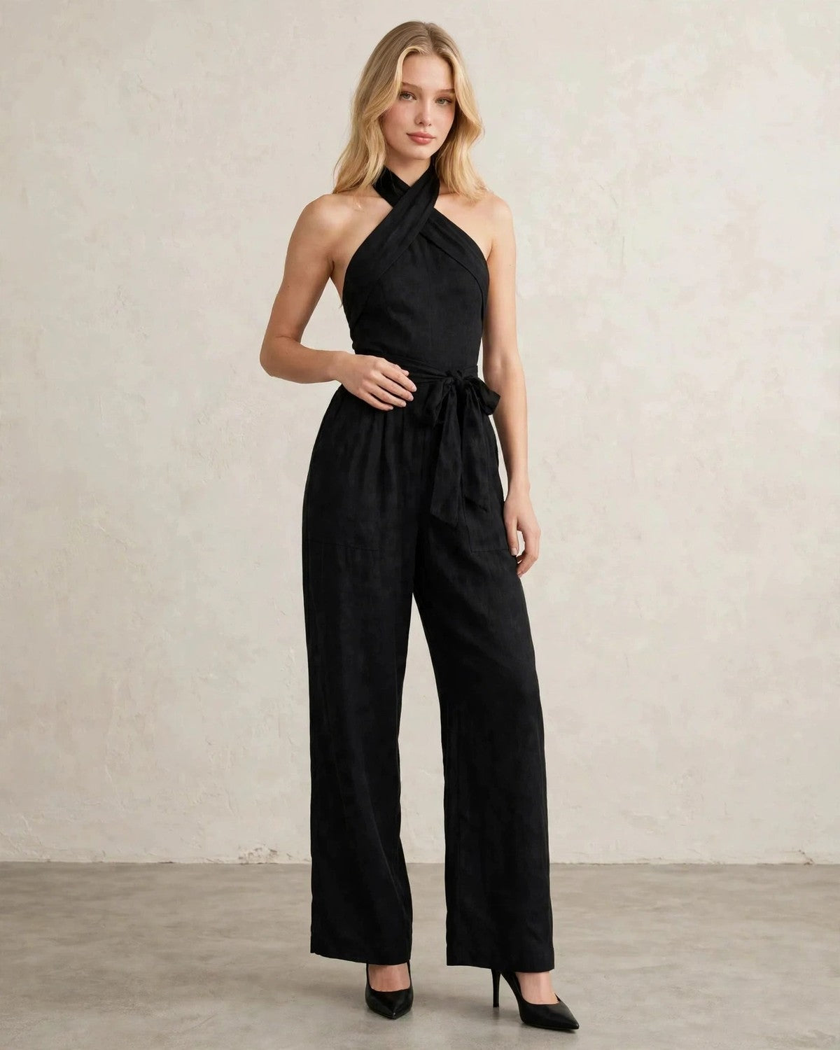 Women's halter neck wide-leg jumpsuit with waist tie in Black, hand at waist pose