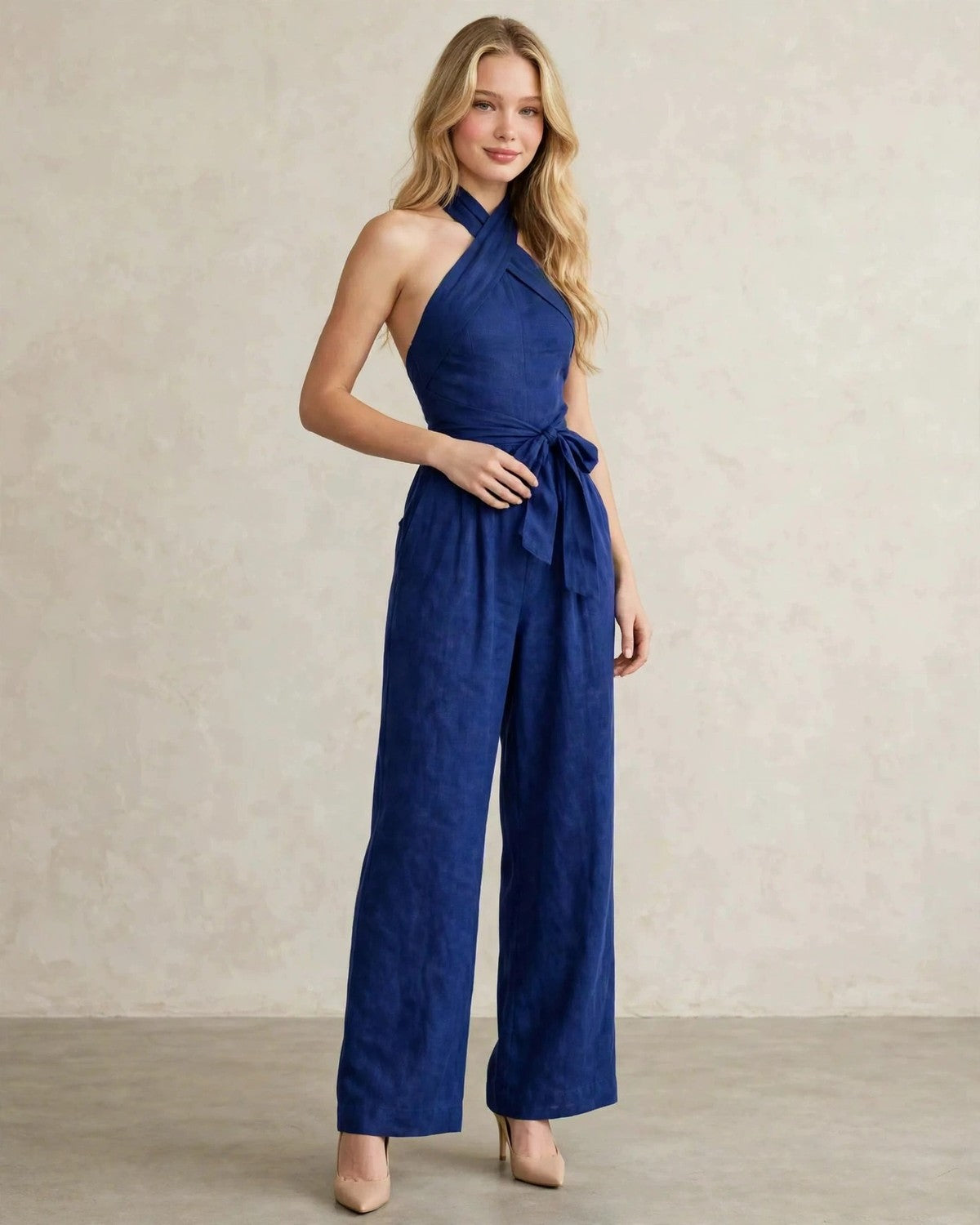 Women's halter neck wide-leg jumpsuit with waist tie in Blue, hand at waist pose