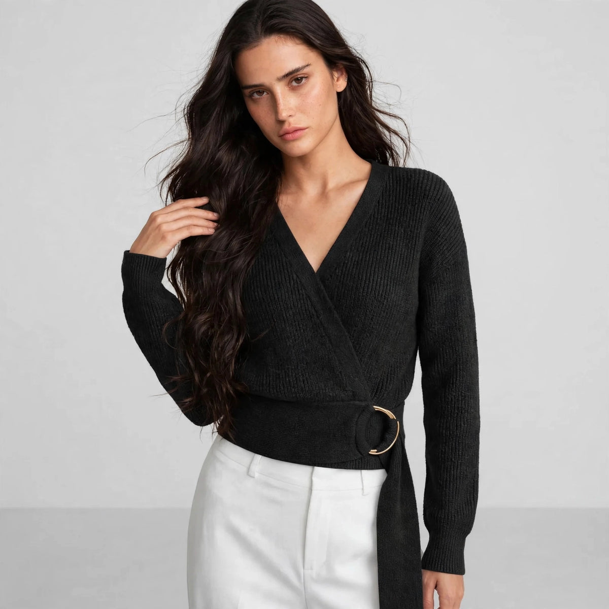 Woman wearing black ring wrap sweater with wrap neckline and gold ring belt