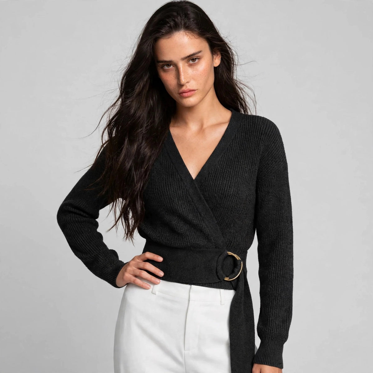 Women's black metal ring wrap sweater, editorial pose, model in wrap knit sweater with gold ring waist tie