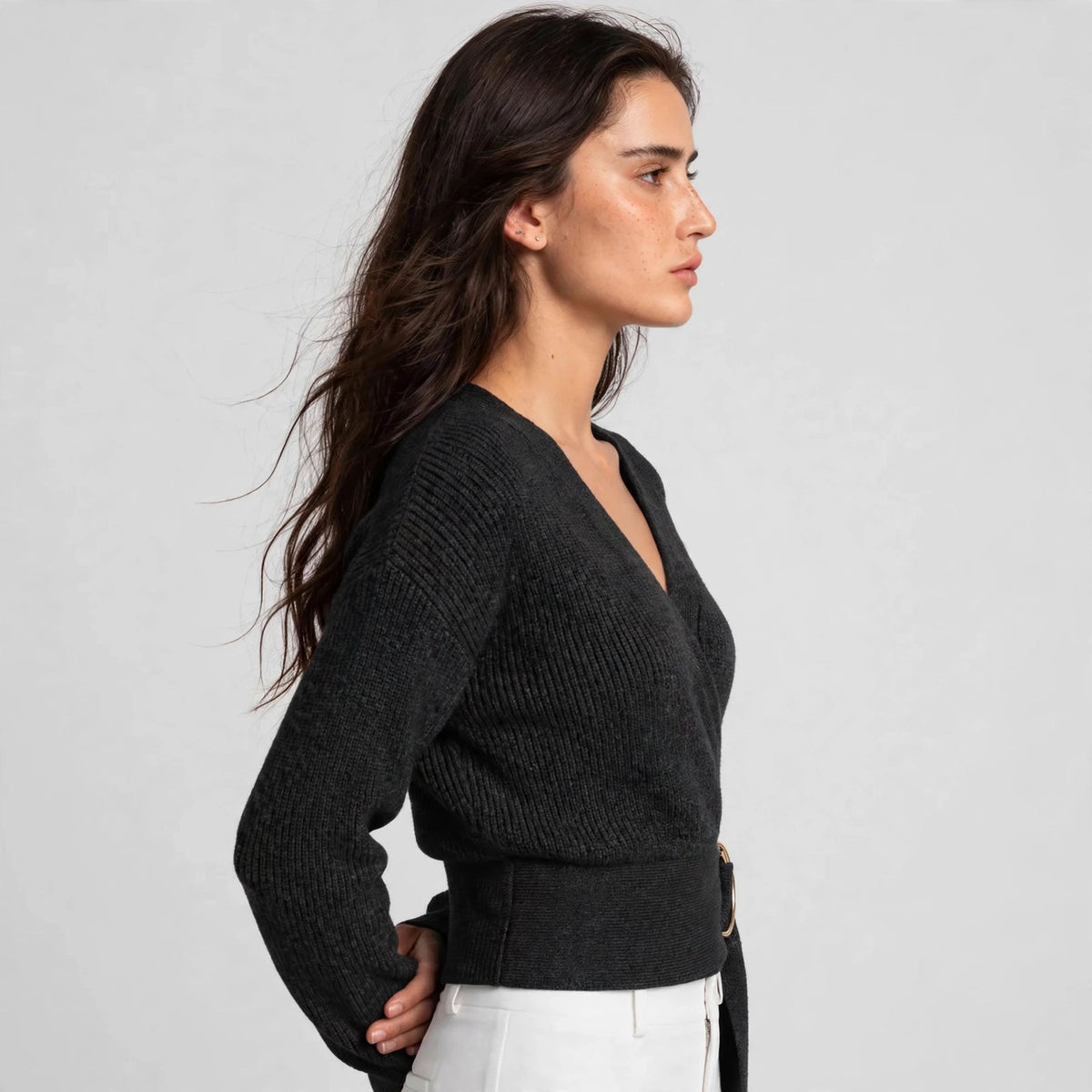 Side view of black ring wrap sweater showing fitted silhouette and belt waist
