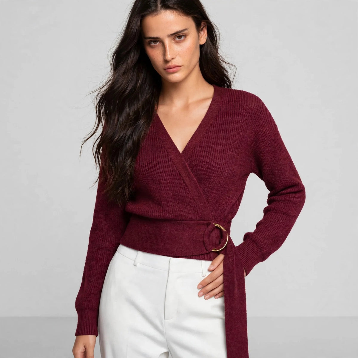 Women's burgundy metal ring wrap sweater, editorial pose, model in wrap knit sweater with gold ring waist tie