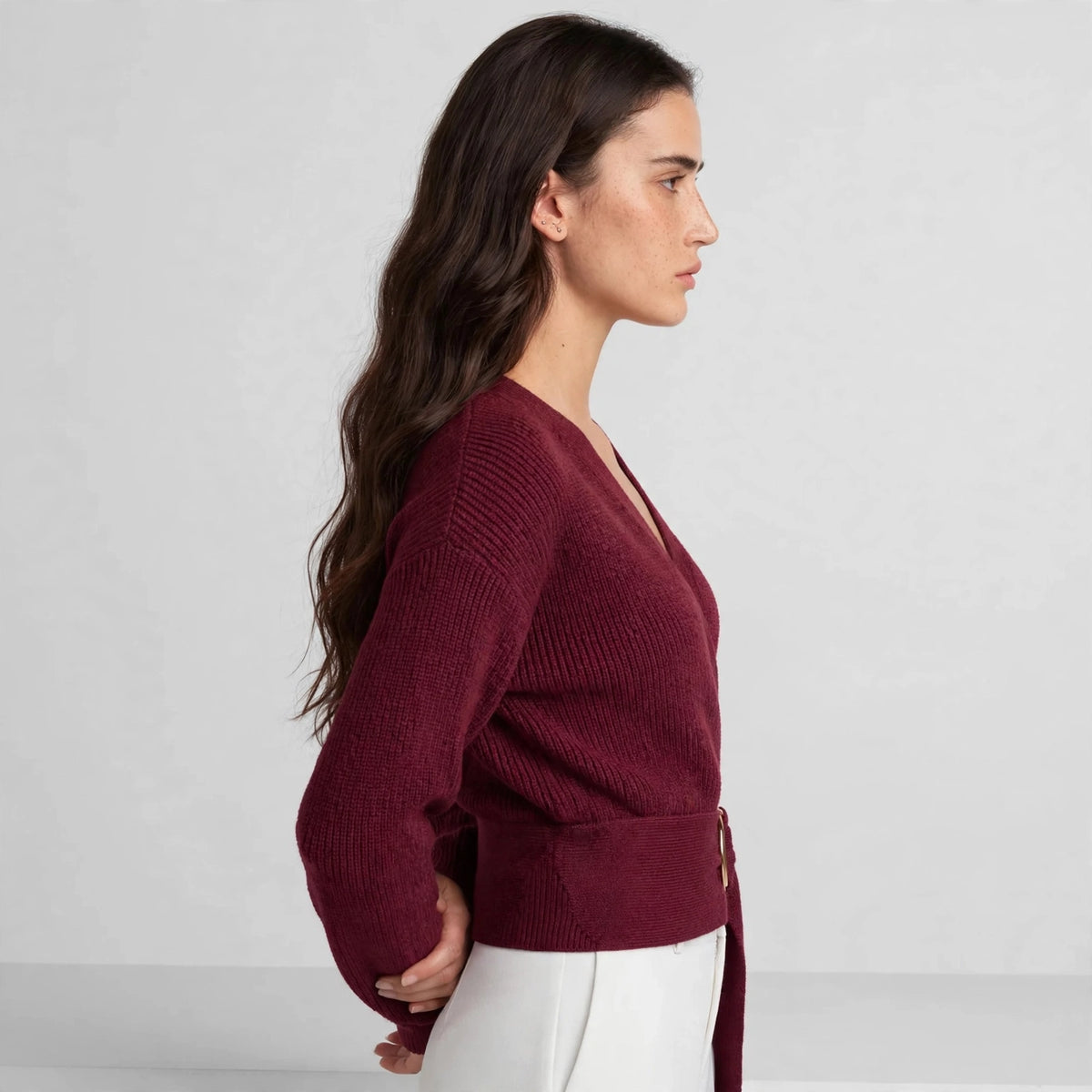 Side view of burgundy ring wrap sweater showing fitted silhouette and belt waist