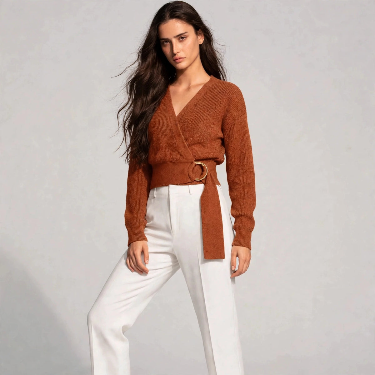 Women's caramel metal ring wrap sweater, editorial pose, model in wrap knit sweater with gold ring waist tie