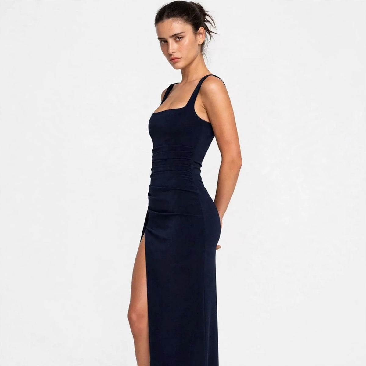 Three-quarter view of a navy blue ruched high-slit maxi dress showing fitted silhouette