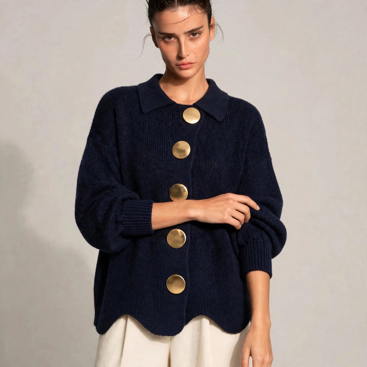 Woman wearing navy gold-button knit cardigan with lantern sleeves, front view