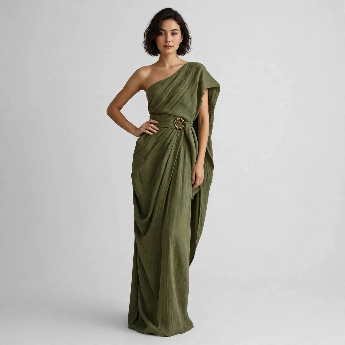 Full-length view of a model with hand on hip in an army green draped one-shoulder maxi dress with a belted ring buckle.