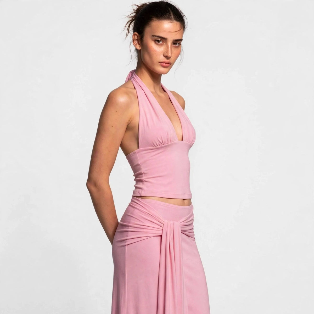 Woman wearing pink halter crop top and draped maxi skirt set