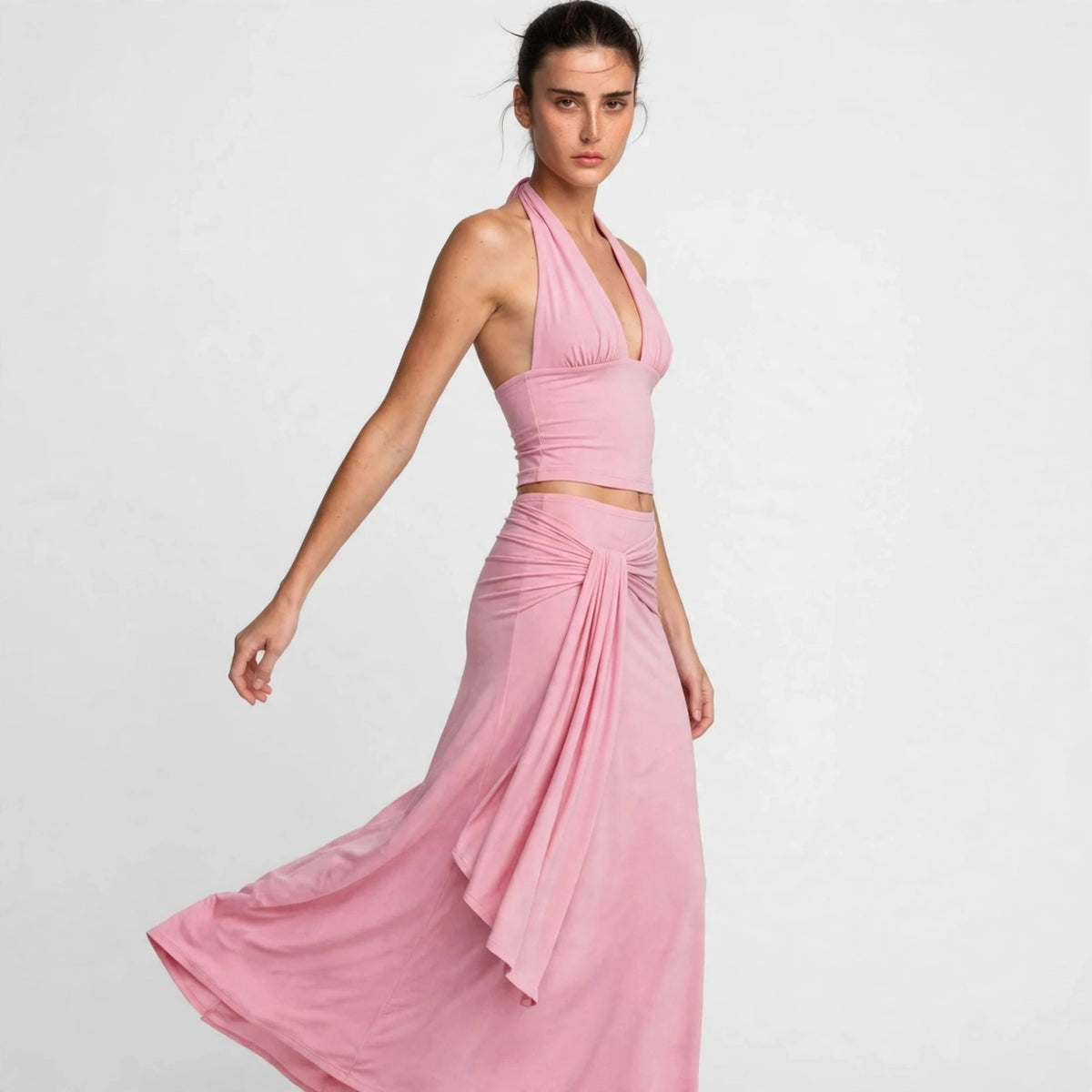 Side view of pink halter skirt set with flowing drape skirt