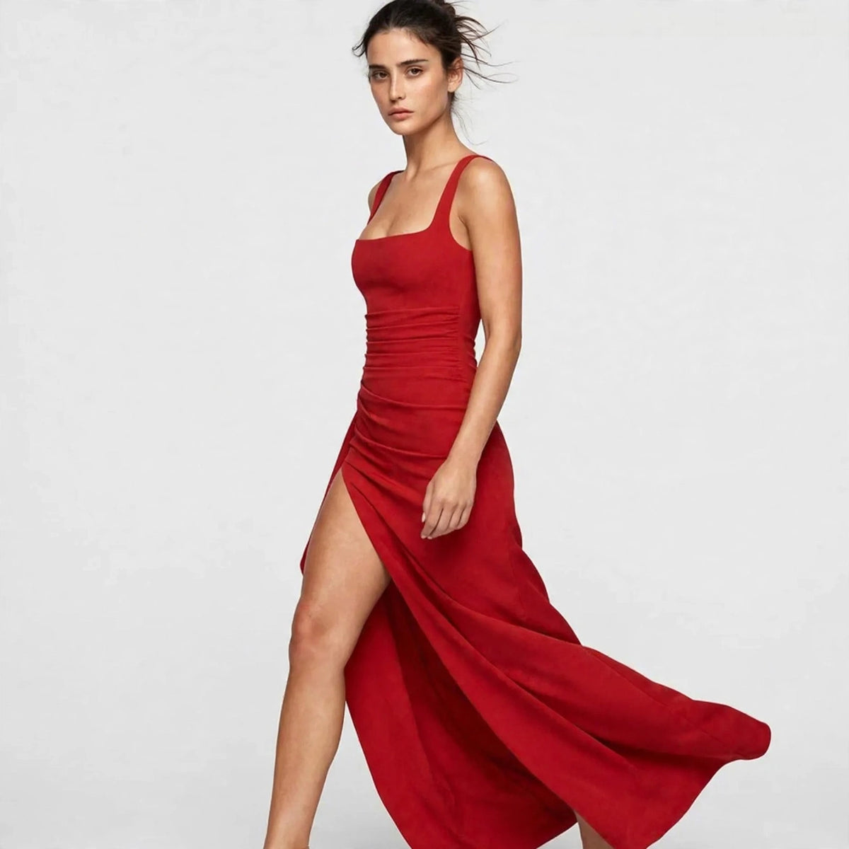 Three-quarter view of a red ruched high-slit maxi dress while walking